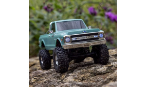 Green SCX30 Chevrolet K10 RC truck on rocky terrain with chrome bumper and realistic grille detailing