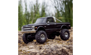 Black SCX30 Chevrolet K10 RC truck on rocky terrain with deep-tread tires and realistic body detailing