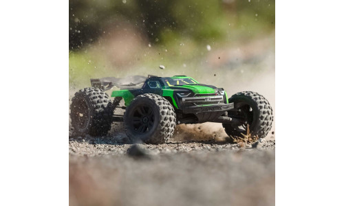 ARA8608V6T3 monster truck bashing through gravel with tires kicking up dust
