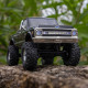 Axial SCX30 Chevrolet K10 RC truck climbing rocks outdoors, showcasing lifted suspension and chrome bumper