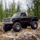 Black SCX30 Chevrolet K10 RC truck on rocky terrain with deep-tread tires and realistic body detailing